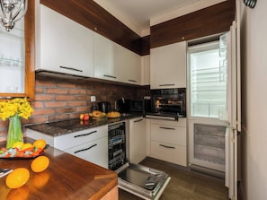 A kitchen with white cabinets, a brick backsplash, a built-in oven, and a dishwasher.