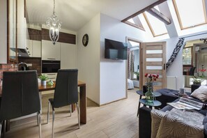 Un espace de vie moderne comprenant un coin repas, un canapé, un téléviseur et une lucarne.