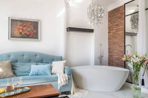Une salle de bain moderne avec une baignoire sur pieds, une douche et un canapé bleu agrémenté de coussins décoratifs.