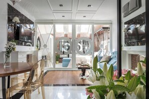A modern interior with a dining area, kitchen, and living space with large windows and a view of the outside. - Glamour studio with free-standing bathtub (Kraków)