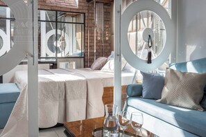 A modern bedroom with a bed, a blue sofa, and a coffee table with glasses.