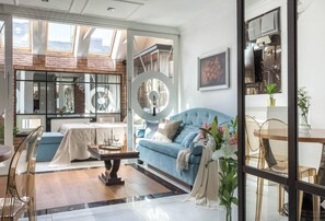 Un salon moderne avec un canapé bleu, une table à manger et un grand miroir.