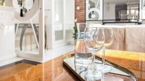 Een modern interieur met een eethoek, bestaande uit een houten tafel met een glazen dienblad waarop wijnglazen en een waterglas staan.