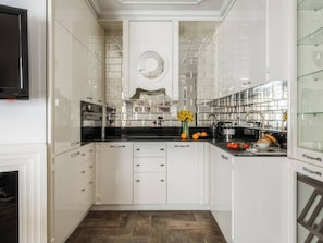 A modern kitchen with white cabinetry, a black countertop, and a central island with a sink.