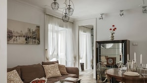 A living room with a brown sofa, a coffee table, and a dining area with a wooden table and chairs. - Glossy 2-bed apartment (Kraków)