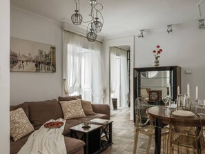 A living room with a brown sofa, a coffee table, and a dining area with a wooden table and chairs.