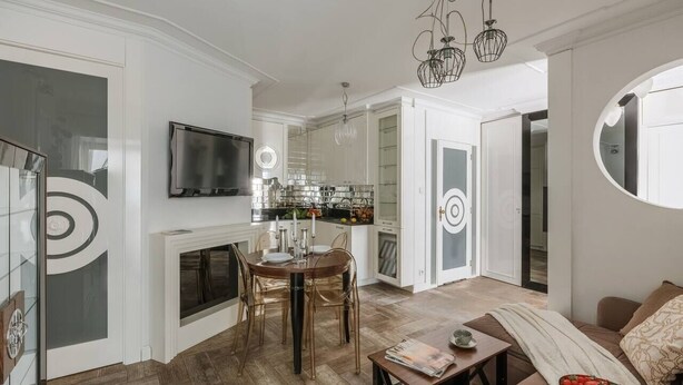 A modern living room with a fireplace, dining area, kitchen, and a large mirror. - Glossy 2-bed apartment (Kraków)