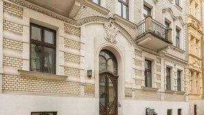A building with a prominent arched entrance, a balcony, and a bicycle parked outside. - Glossy 2-bed apartment (Kraków)