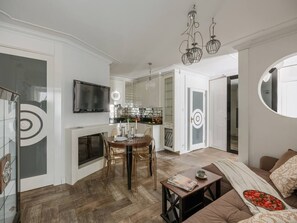 A modern living room with a fireplace, dining area, kitchen, and a large mirror.