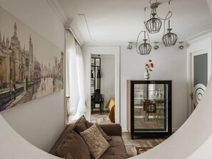 Una sala de estar con un sofá, un aparador de vidrio y un cuadro en la pared.