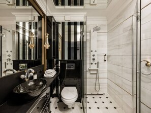 A modern bathroom with a black vanity, a glass shower enclosure, and a white toilet.