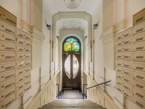 Um amplo corredor com uma janela central de vitrais, ladeado por fileiras de armários numerados.