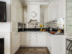A modern kitchen with white cabinetry, a black countertop, and a central island with a sink.