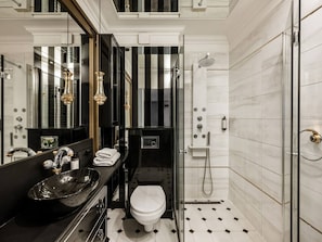 A modern bathroom with a black vanity, a glass shower enclosure, and a white toilet.