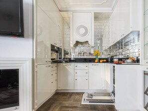 Uma cozinha moderna com armários brancos, forno embutido e exaustor de aço inoxidável.