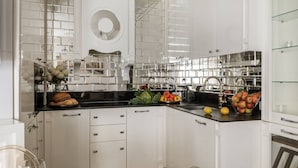 A modern kitchen with white cabinets, a black countertop, and a glass backsplash. - Glossy 2-bed apartment (Kraków)