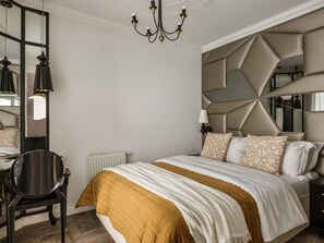 Un dormitorio con cama, escritorio, silla, espejo y candelabro.