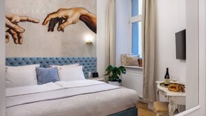A bedroom with a large bed, a wall mural, a window with curtains, a bedside table with a bottle and glasses, and a plant. - Magnifique 2-bed apartment (Kraków – Old Town)