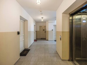 Un couloir d ’hôtel avec une porte, un ascenseur et un sol carrelé.