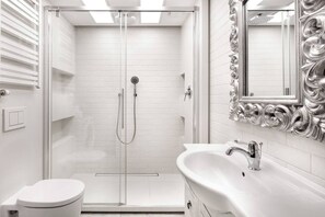 A modern bathroom with a glass-enclosed shower, a white sink with a mirror, and a toilet.
