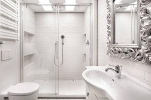A modern bathroom with a glass-enclosed shower, a white sink with a mirror, and a toilet.