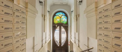 A grand hallway with a central stained glass window, flanked by rows of numbered storage lockers.