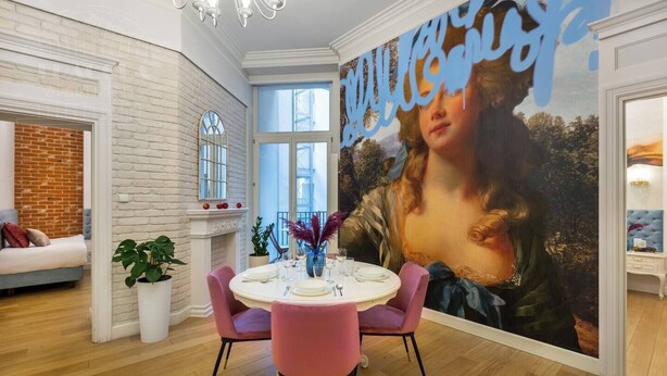 A dining area with a round table, chairs, and a large painting on the wall. - Magnifique 2-bed apartment (Kraków – Old Town)