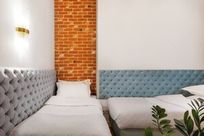 Une chambre avec deux lits, un mur en briques et un luminaire moderne.