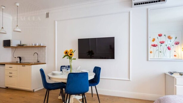 A modern kitchen with white cabinets, a wooden countertop, and a built-in oven. - Poppy studio with balcony (Kraków)