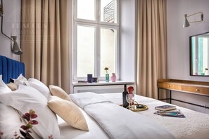A hotel room with a bed, bedside table, window, and a view of the outside.