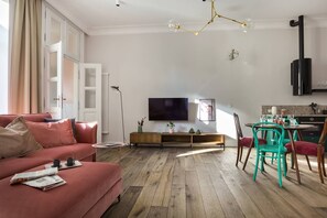 Una sala de estar con sofá, una mesa de comedor con sillas, televisor y espacio de cocina.