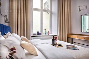 A hotel room with a bed, bedside table, window, and a view of the outside. - Apartment Pink Velvet with sauna and bathtub (Kraków)