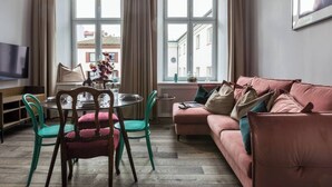 A living room with a sofa, chairs, a dining table, and a TV. - Blue Suede apartment (Kraków – Old Town)