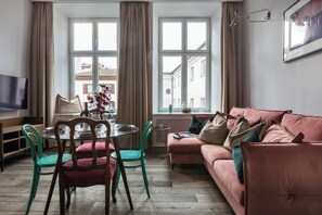 A living room with a sofa, chairs, a dining table, and a TV. - Blue Suede apartment (Kraków – Old Town)