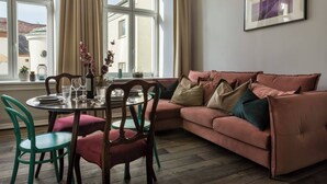 A living room with a sofa, chairs, a dining table set, and a window with curtains. - Blue Suede apartment (Kraków – Old Town)