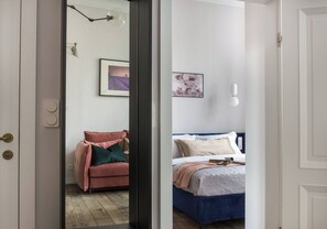 A room with a bed, a chair, and a wall-mounted light fixture. - Blue Suede apartment (Kraków – Old Town)