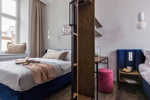 Una habitación de hotel moderna con cama, mesita de noche y una ventana con cortinas.