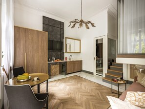 A modern kitchen with a built-in oven, a dining area with a herringbone floor pattern, and a staircase leading to an upper level. - Blush Pink apartment with sauna and terrace (Kraków)