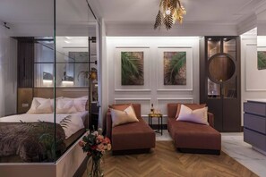 Un dormitorio moderno con una cama, dos sofás, una mesita y obras de arte en las paredes.