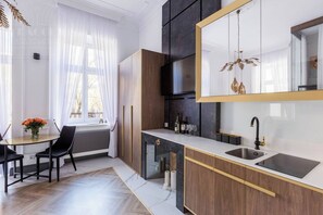 Cozinha moderna com um espelho grande, armários escuros e um espaço de refeições com mesa e cadeiras.