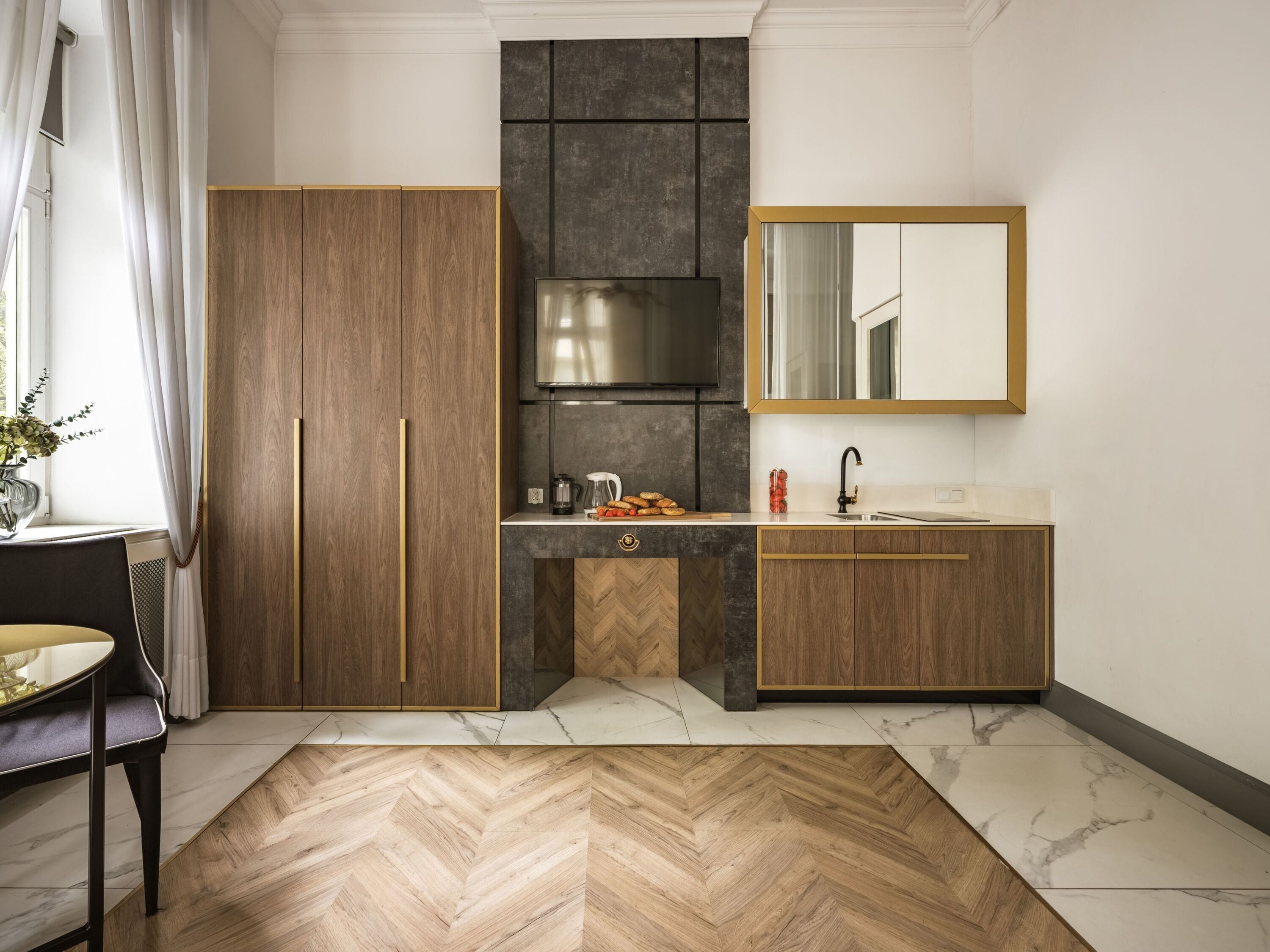 A modern kitchen with wooden cabinets, a built-in stove, and a marble countertop.
