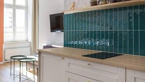 A modern kitchen with a teal backsplash, wooden countertop, and a flat-screen TV mounted above the sink. - Funky studio 10 min to Main Square (Kraków – Old Town)