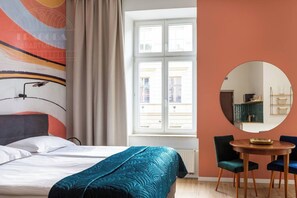 A hotel room with a bed, a round table with chairs, a window with curtains, and a wall-mounted mirror. - Funky studio. - One Bedroom Apartment, Sleeps 2 (Kraków – Old Town)