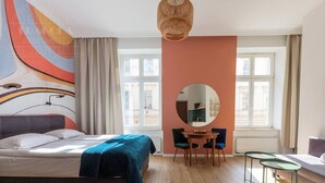 A bedroom with a bed, a round mirror, a dining table with chairs, and a window. - Funky studio 10 min to Main Square (Kraków – Old Town)