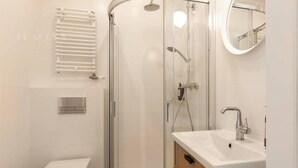 A modern bathroom with a glass-enclosed shower, a white toilet, and a vanity with a mirror. - Funky studio 10 min to Main Square (Kraków – Old Town)