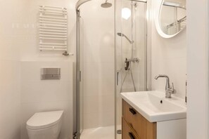 A modern bathroom with a glass-enclosed shower, a white toilet, and a vanity with a mirror. - Funky studio. - One Bedroom Apartment, Sleeps 2 (Kraków – Old Town)