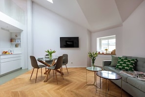 Un espacio de estar moderno con comedor, sofá y televisor montado en la pared.