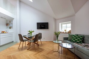 Un espacio de estar moderno con comedor, sofá y televisor montado en la pared.