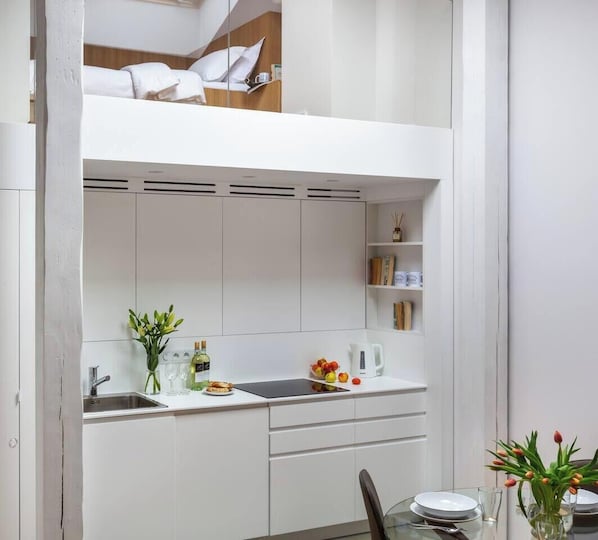 A compact kitchen with a dining area, a built-in bed, and a small bookshelf.