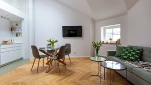 Un espace de vie moderne comprenant un coin repas, un canapé et un téléviseur fixé au mur.